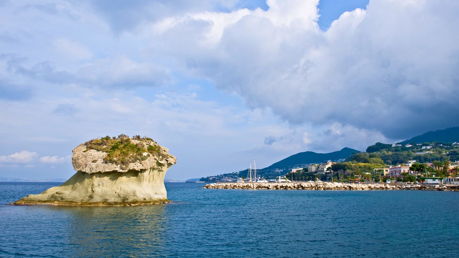 Il Fungo di Lacco Ameno Ischia: la caratteristica roccia vulcanica a forma di fungo che emerge dal mare davanti al porto con il paese sullo sfondo